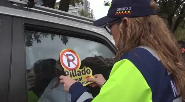 Carro mal parqueado en Bogotá con sticker "Pillado mal parqueado"
