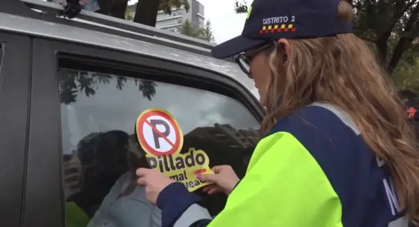 Carro mal parqueado en Bogotá con sticker "Pillado mal parqueado"